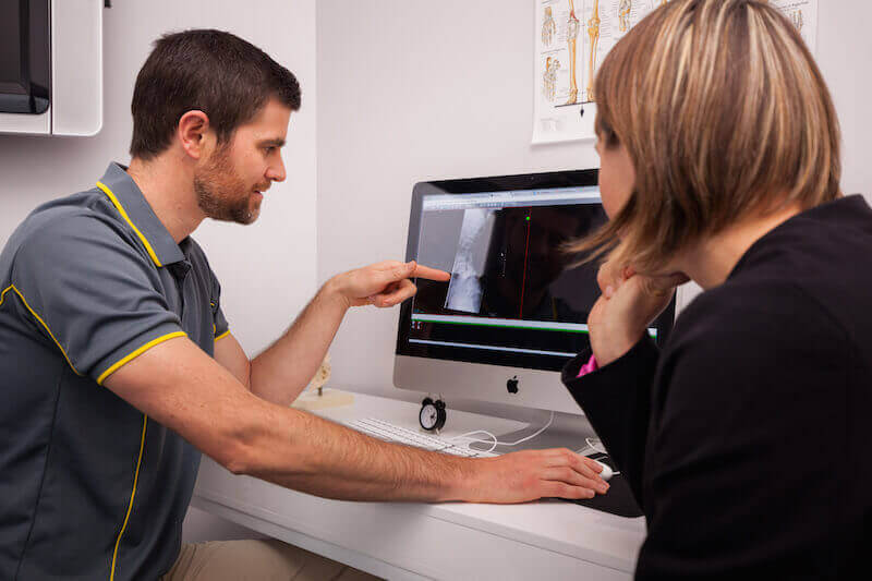 Doctor Is Showing Osteopath Report To Their Patients On Computer